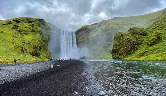 Students play in the water with a waterfall in the background.