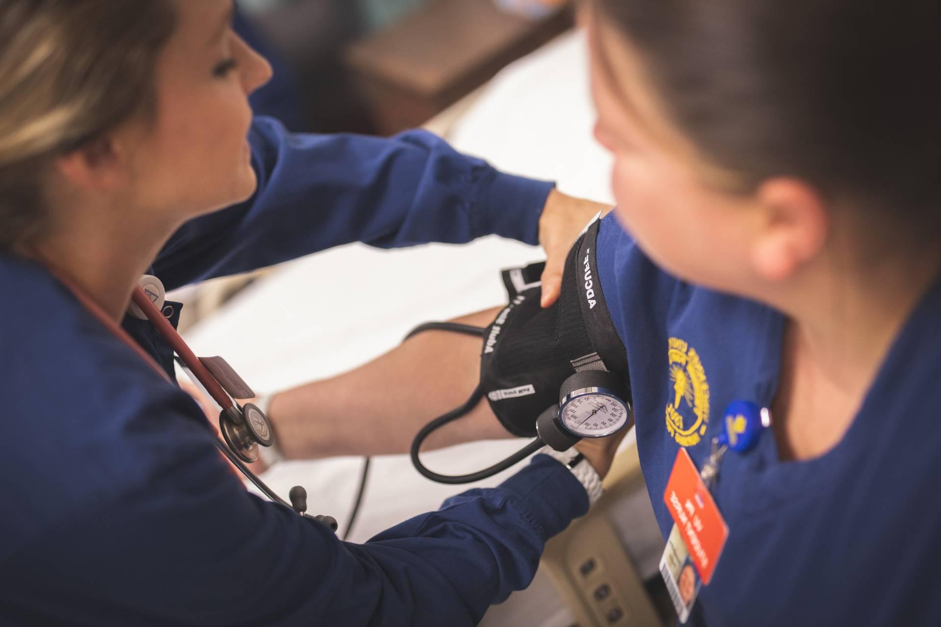 A nursing student measuring the blood pressure of another student